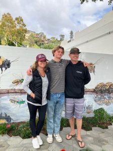 Merrick Vellmure, recipient of first Bee Day Award with his parents in front of Willey bee mural